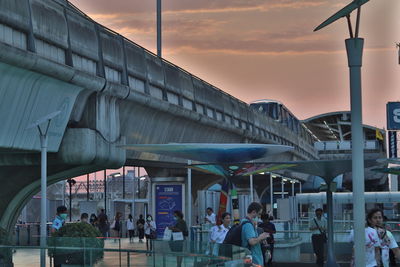 People in city against sky during sunset