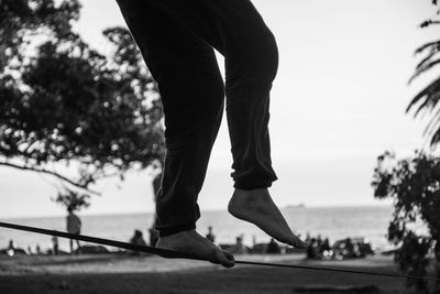 Low section of person by tree against sky