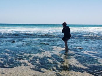 Side view of man on beach against clear sky