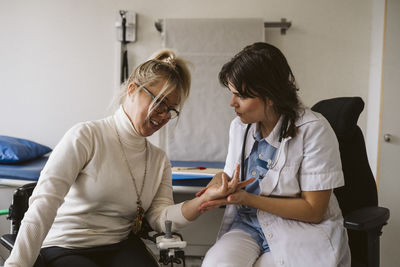 Female medical expert checking pulse of disabled patient in medical clinic