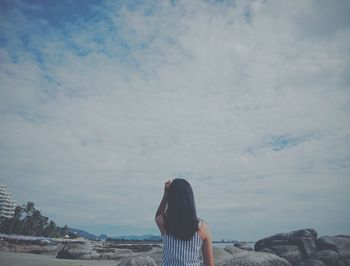 Rear view of woman at beach in city against sky