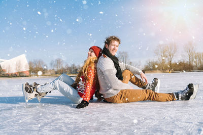 Portrait of young woman sitting on snow covered field