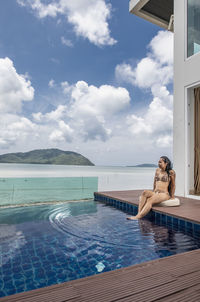 Beautiful woman sitting by the pool at luxury villa in phuket