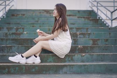 Side view of woman sitting on staircase