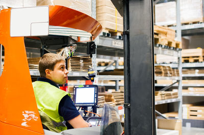 Worker driving forklift in factory