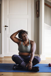 Mature woman with eyes closed practicing relaxation exercise on mat at home