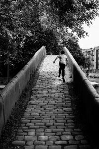 Man walking on retaining wall against sky