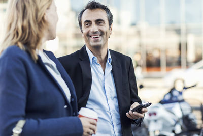 Happy businessman talking to female colleague outdoors