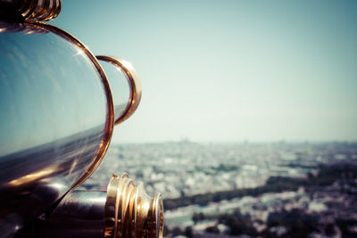 Coin-operated binoculars by cityscape against sky