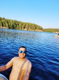 Portrait of shirtless man against blue sky