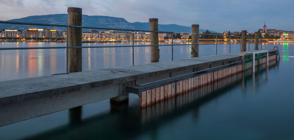 Pier over lake in city at dusk