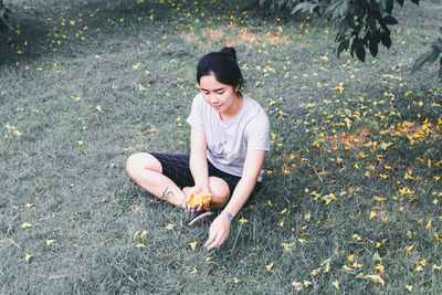 High angle view of woman sitting on field during autumn