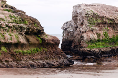 Rock formation on sea shore against sky