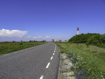 Road amidst trees against blue sky