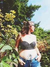 Midsection of woman standing by tree against plants