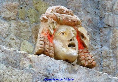 Close-up of statue on rock against wall