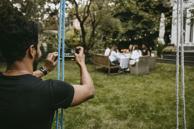 Rear view of man photographing at camera