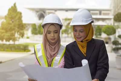 Female architects examining blueprint on street