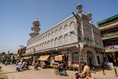 People on street against buildings in city