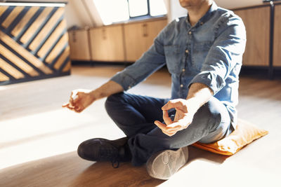 Low section of woman sitting on hardwood floor