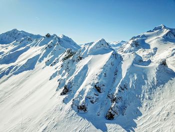 Scenic view of snowcapped mountains against clear blue sky