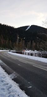 Road by snow covered city against sky