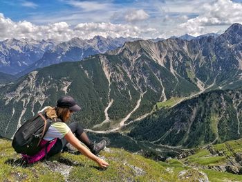 Woman sitting on mountain against sky