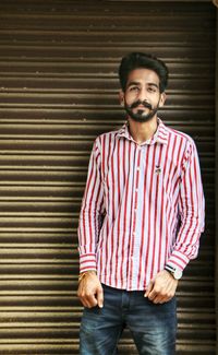 Portrait of a smiling young man standing against shutter