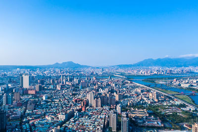 High angle view of illuminated city buildings against blue sky