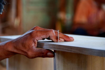 Cropped hand of carpenter by nail on wood