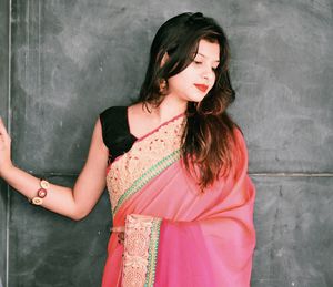 Woman in pink sari while standing against wall