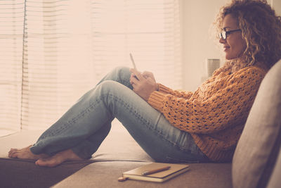 Woman sitting and using phone at home