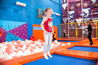 Full length of girl standing against blue wall