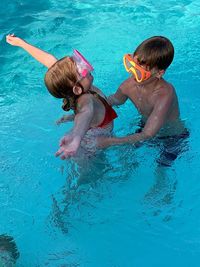High angle view of siblings swimming in pool