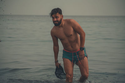 Full length of shirtless man standing on beach