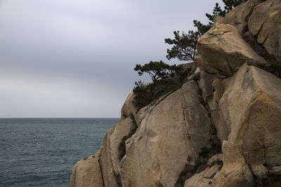 Rock formation by sea against sky