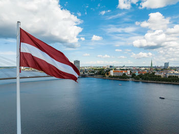 Latvian flag with the dome cathedral and an old town in the background