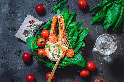 A plate with fresh green raw spinach and fried wild salmon, tomatoes and cream cheese sauce 