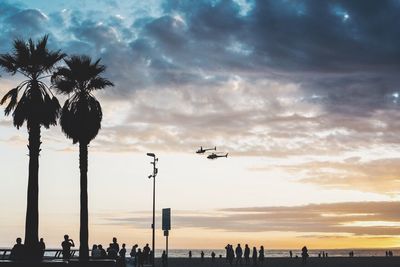 Rescue helicopter hovering over sea at sunset