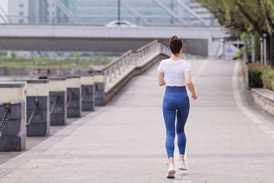 Rear view of woman standing on footpath