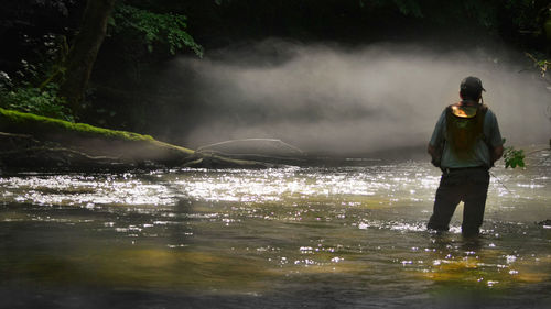 Full length of man standing by waterfall against sky