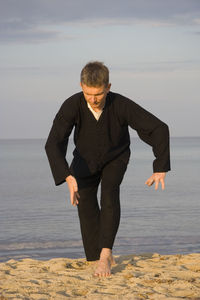 Full length of man practicing tai chi on sand at beach