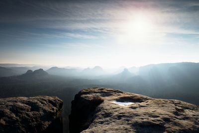 Blue spring daybreak. sandstone cliff above deep misty valley in saxony switzerland. hilly peaks 