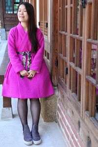 Full length of woman standing by house