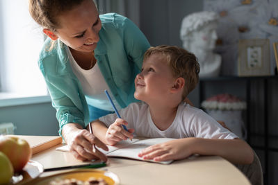 Happy mother and son drawing together