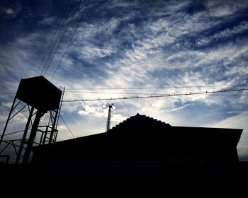 Low angle view of silhouette electricity pylon against sky at sunset