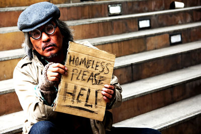 Beggar holding placard while sitting on steps