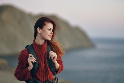 Young woman looking away while standing in sea