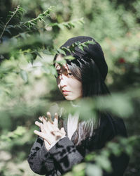 Close-up of young woman with hand on tree