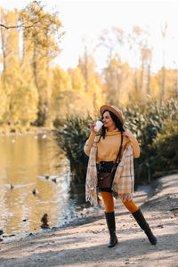 Beautiful smiling girl in casual clothes drinking coffee walking in nature in autumn outdoor